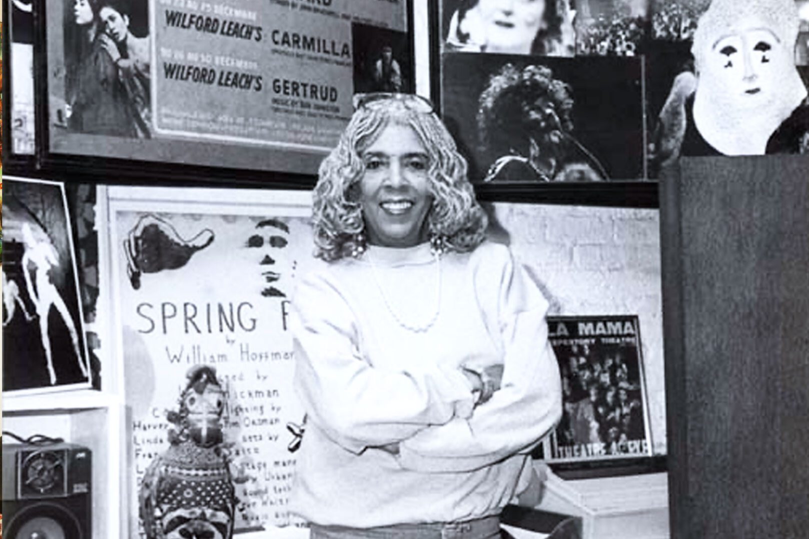 A black and white photo of a woman standing in front of a room full of posters.