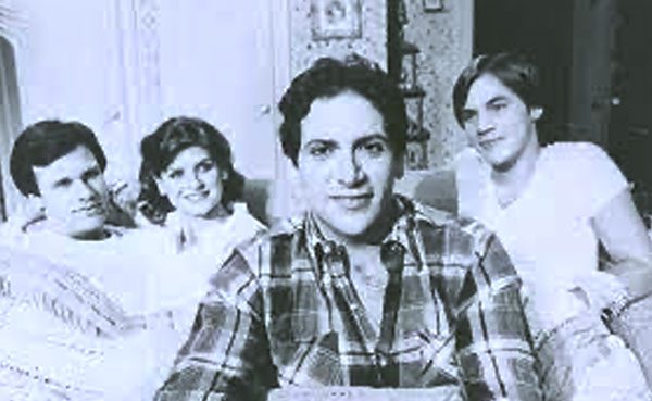 A black and white photo of a group of people sitting on a couch.