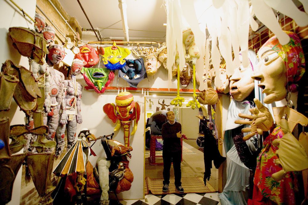 A woman is standing in a room full of masks.