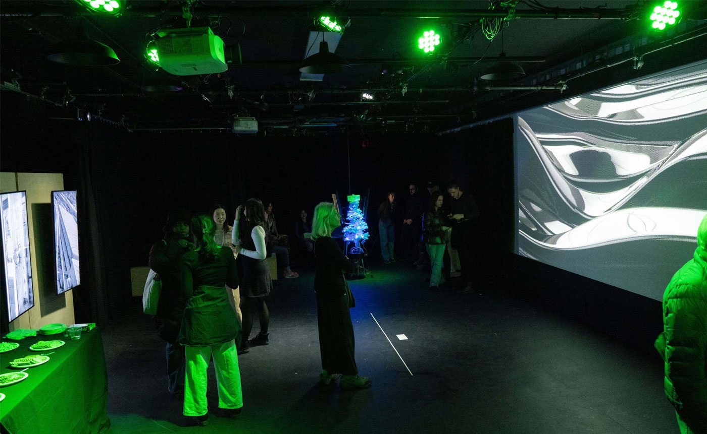 A group of people viewing digital artwork in a dimly lit gallery with green ambient lighting and a large screen displaying abstract visuals.