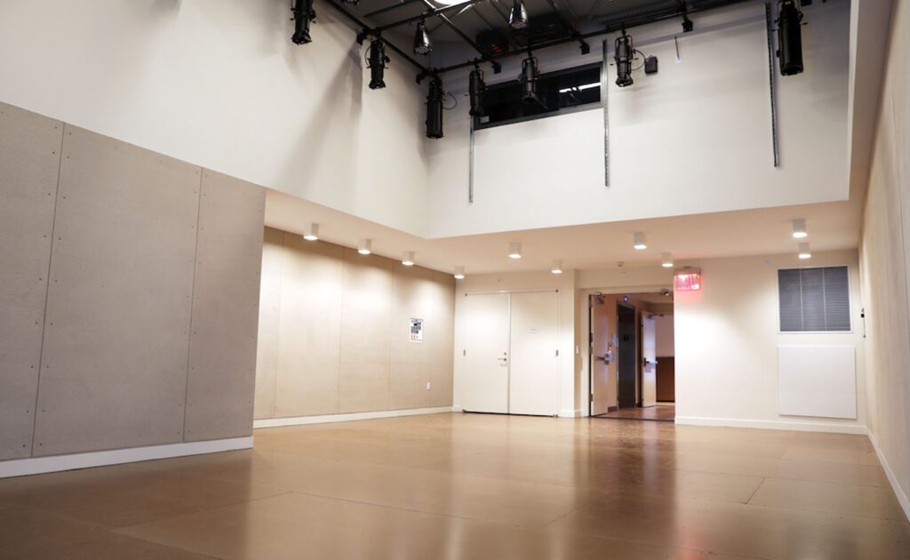 Modern empty hallway with beige walls, wooden flooring, white doors, and lighting fixtures mounted on the ceiling.