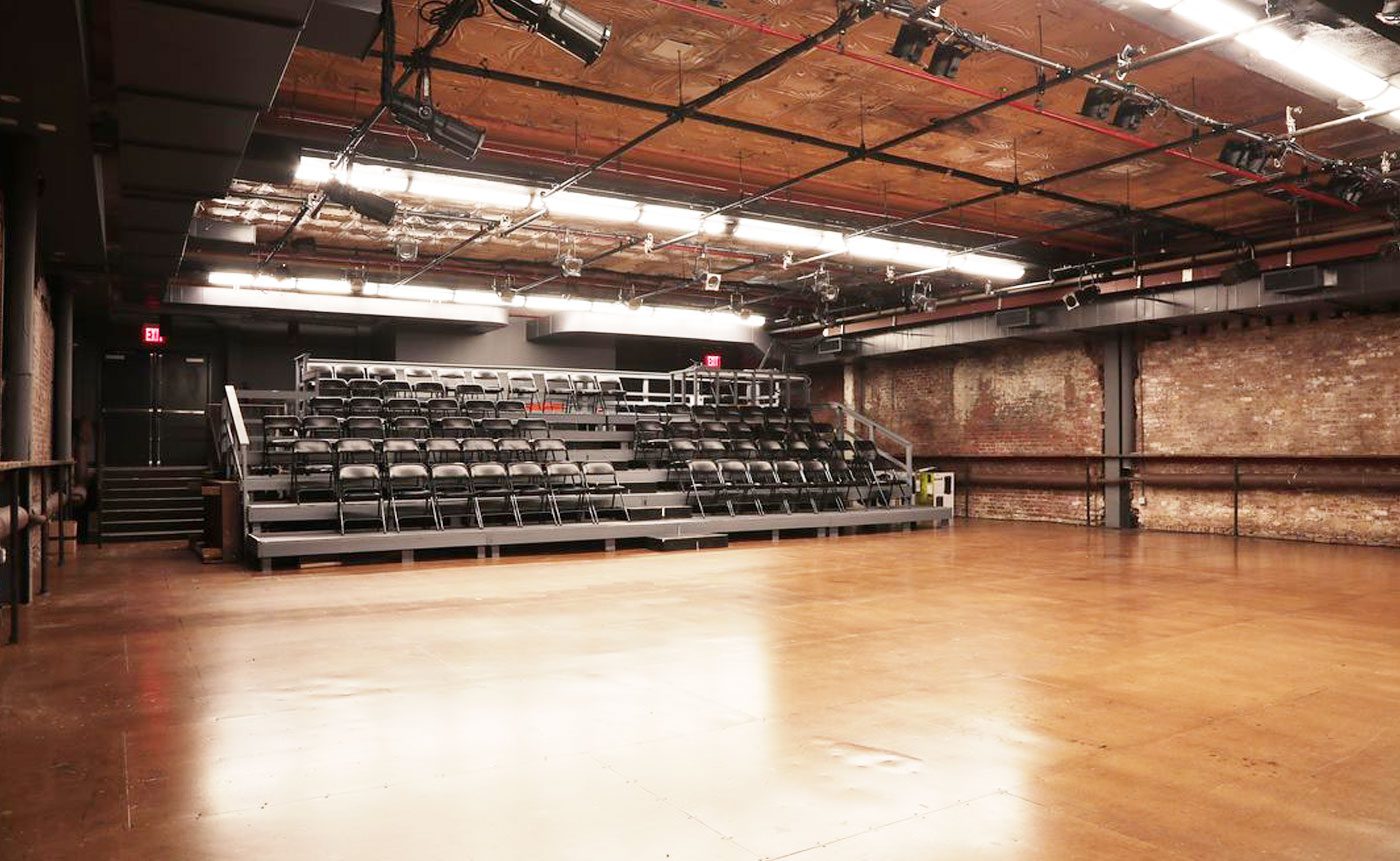 Empty stage with seating and wood floor.