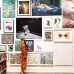 A woman standing in front of a wall full of pictures.