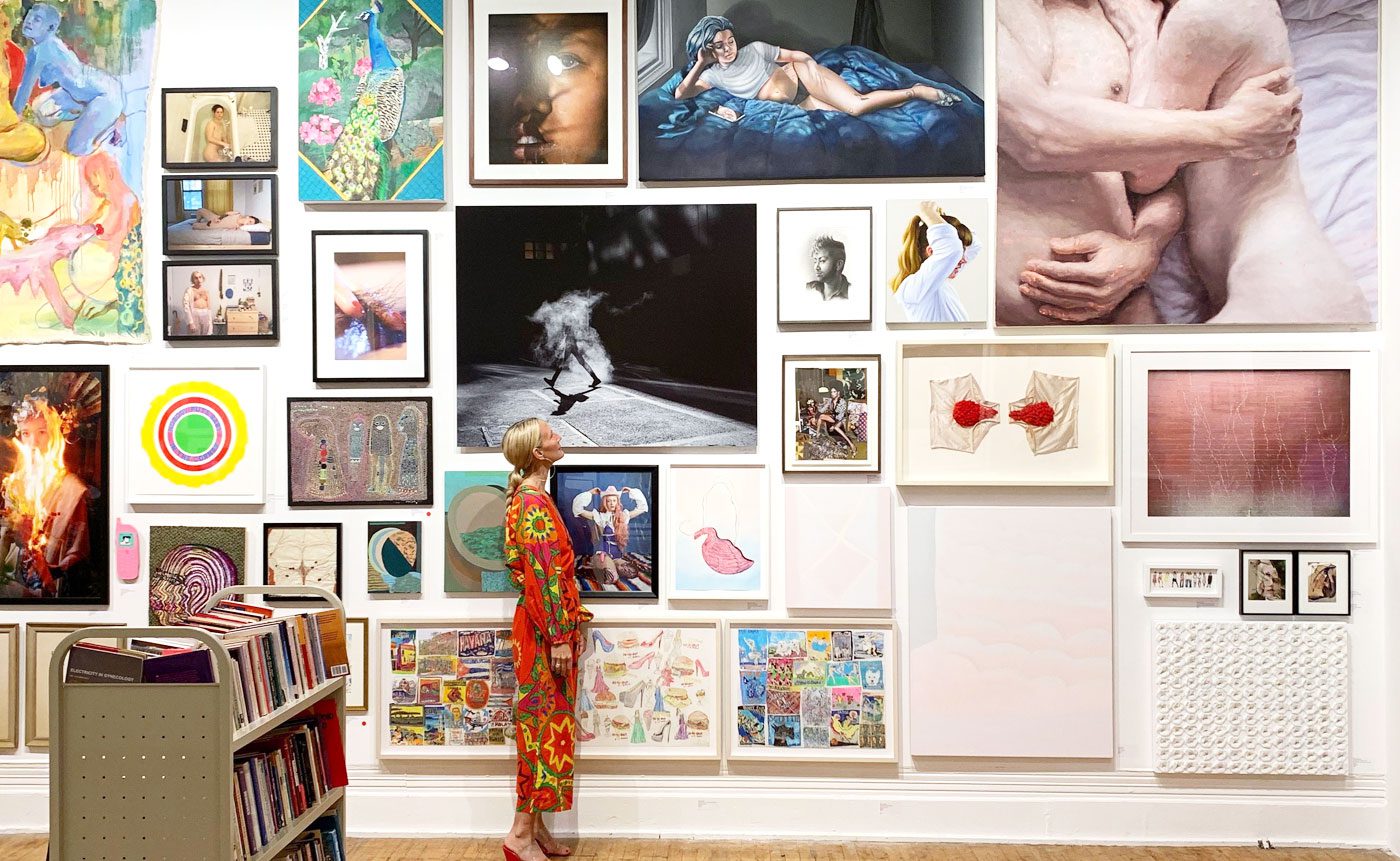 A woman standing in front of a wall full of pictures.