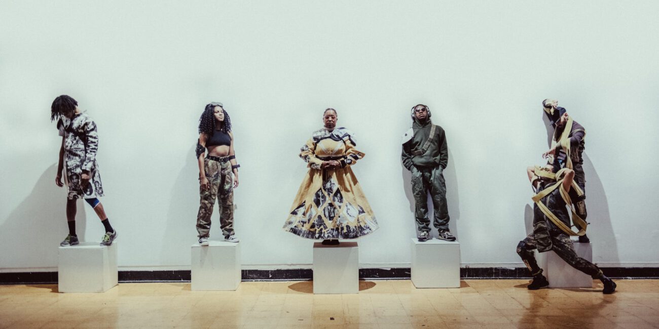 A group of people standing in front of a white wall.