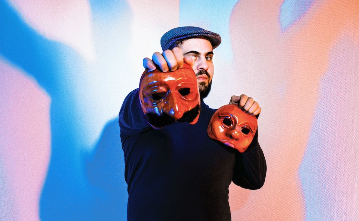 Man holding two red theatrical masks.