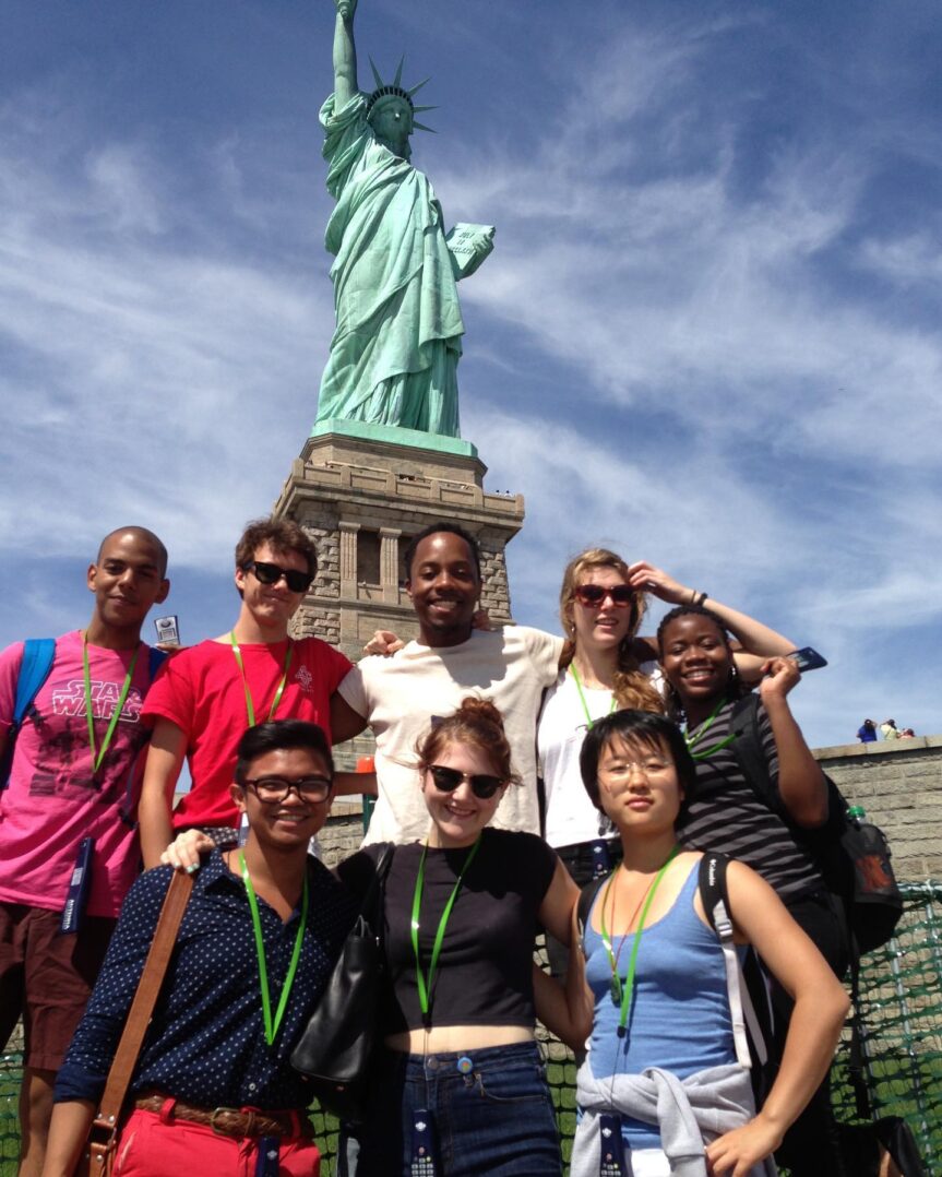 A group of people posing in front of the statue of liberty.