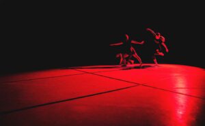 A group of dancers on a stage in a dark room.