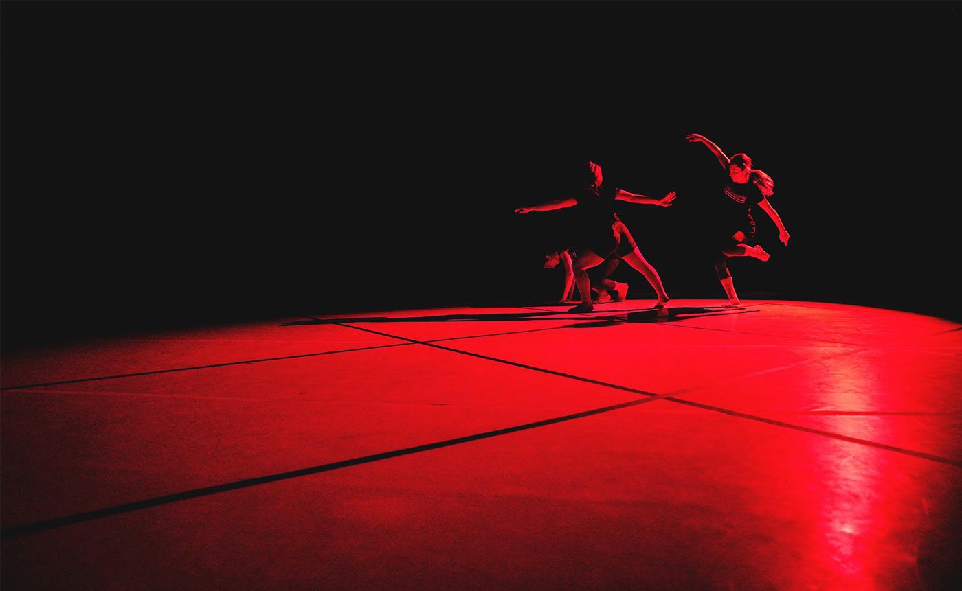 A group of dancers on a stage in a dark room.