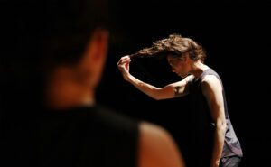 A woman with her hair blowing in the air in a dark room.