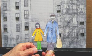 A person holding a paper cut out of a man and woman.