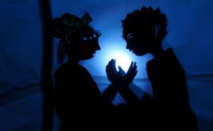 A silhouette of a couple holding hands in front of a light.