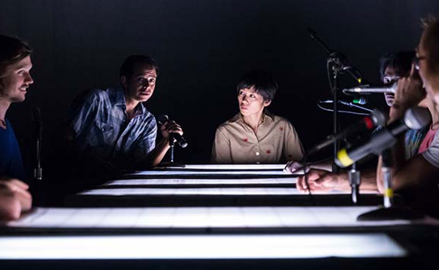 A group of people sitting around a table in a dark room.