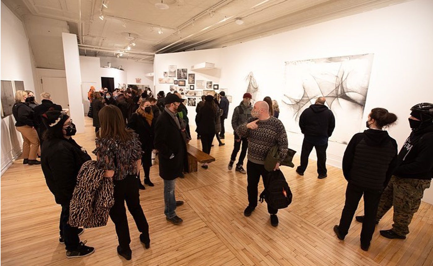 A group of people standing in an art gallery.