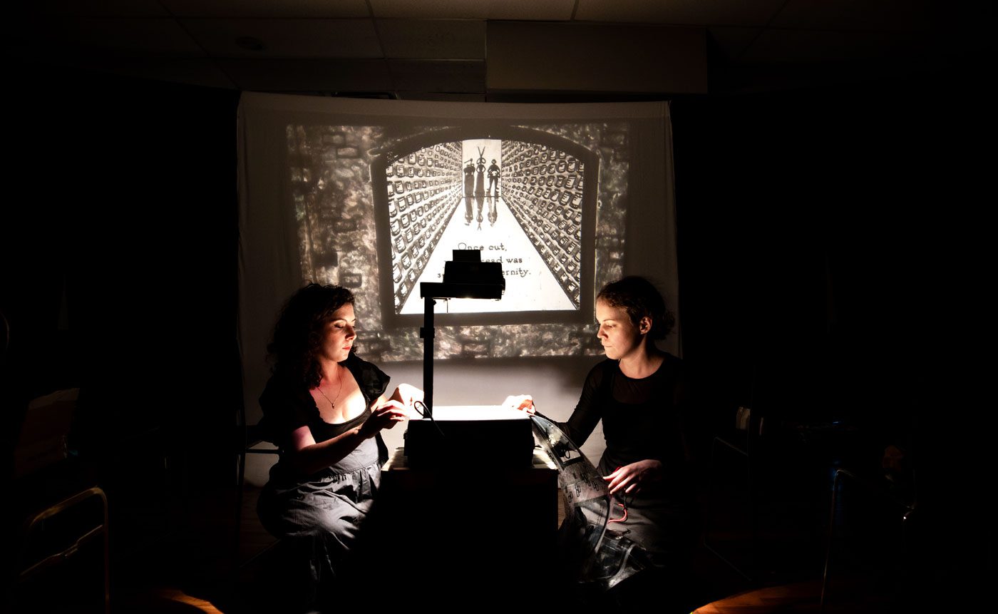 Two women watching a projected story.