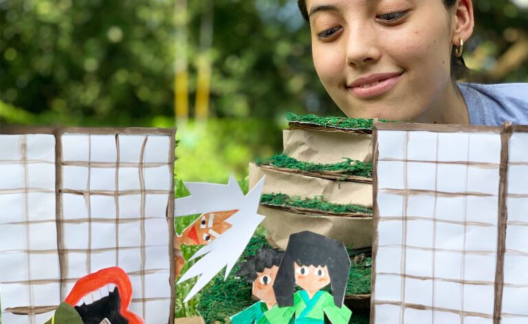 A girl is looking at a paper model of a house.