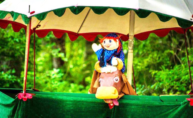 A stuffed animal riding a horse under an umbrella.