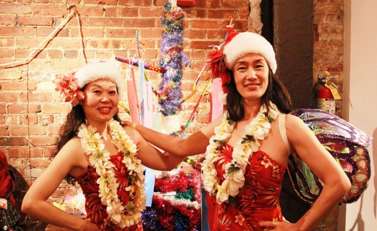 Two women in hawaiian costumes pose for a photo.