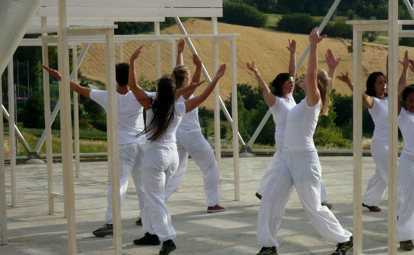 A group of people in white doing yoga on a roof.