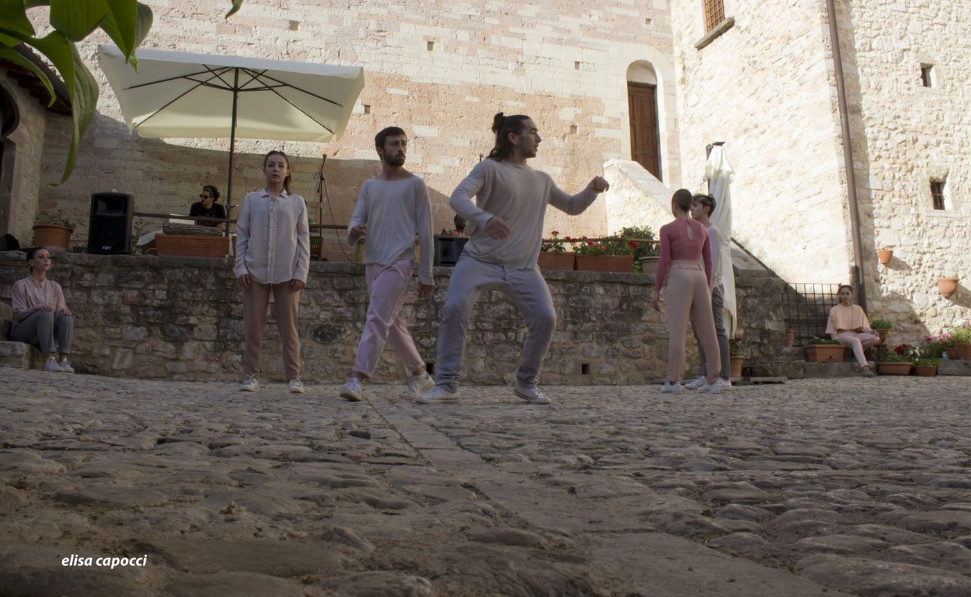 A group of people are dancing on a cobblestone street.