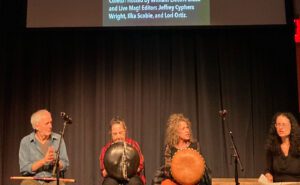 A group of people sitting on stage with drums.