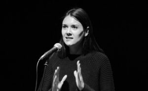 A black and white photo of a woman speaking into a microphone.