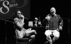 A man and a woman sitting in front of a microphone.