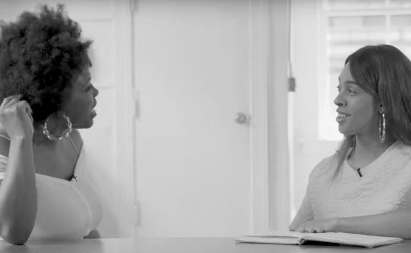 Two women sitting at a table talking to each other.