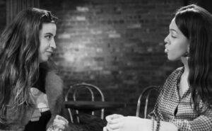 Two women sitting at a table talking to each other.