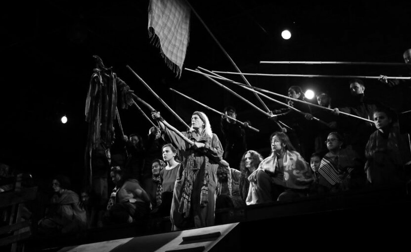 A black and white photo of a group of people holding sticks.